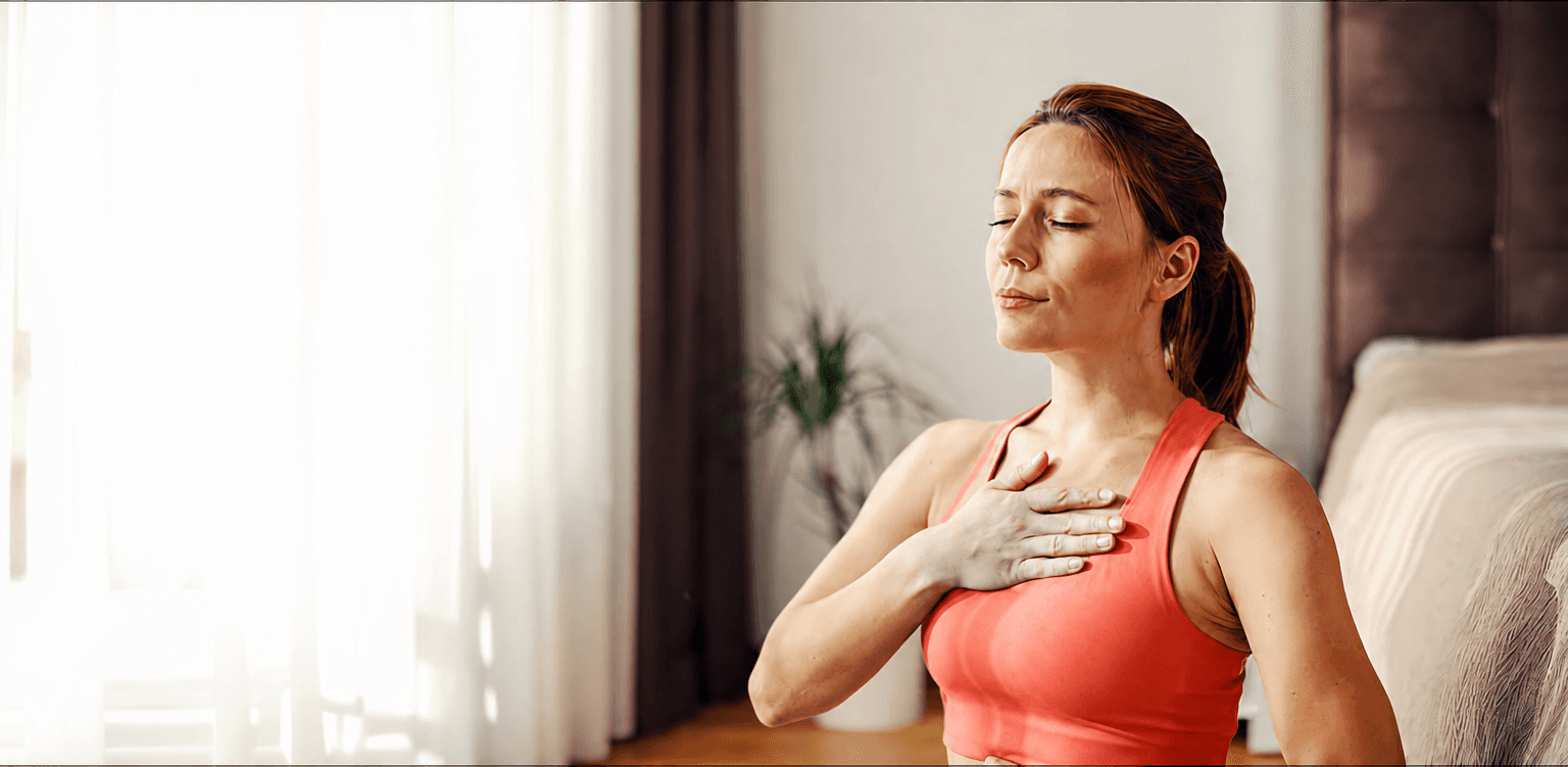 woman in coral tank top resting a hand on her chest with eyes closed